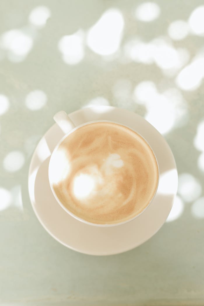 A beautifully crafted latte showcasing intricate foam art in a sunlit café setting, perfect for coffee lovers.