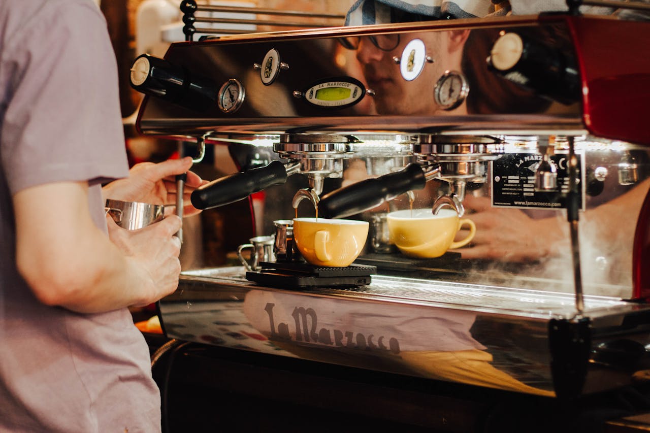who-we-are Barista using espresso machine to brew coffee in a café, showcasing coffee preparation process.